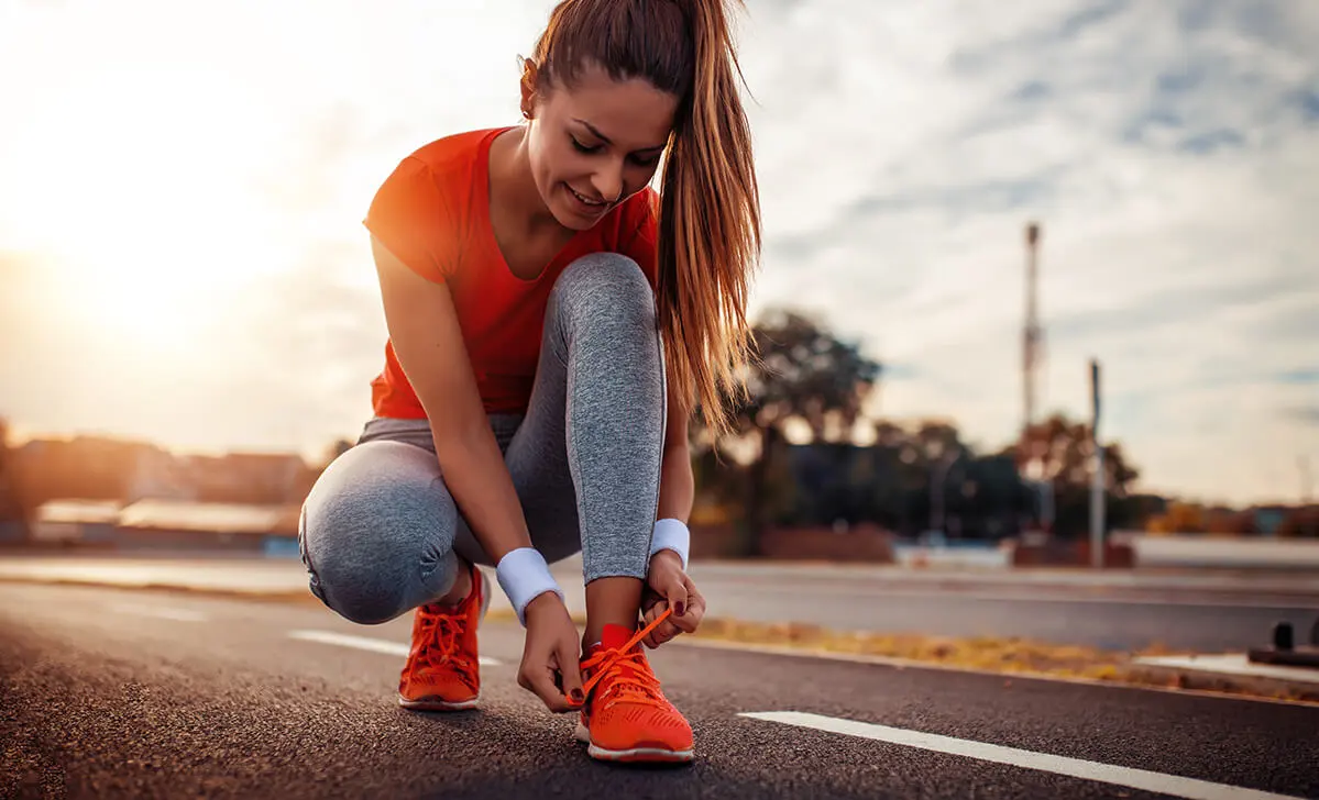 A runner tying a shoe during a fitting